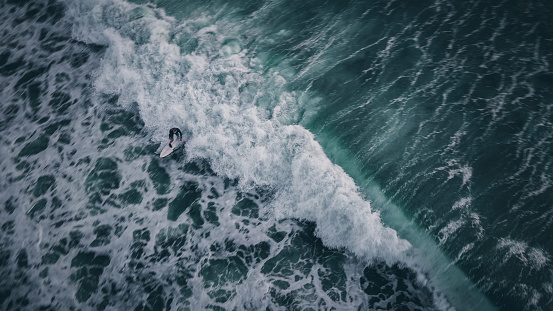 Aerial view of a man surfing the waves in Bali, Indonesia