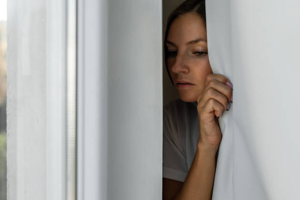 Woman scared looking through the window seeking safety Woman scared looking through the window seeking safety Phobia stock pictures, royalty-free photos & images