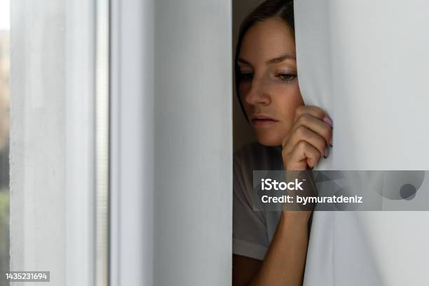 Woman Scared Looking Through The Window Seeking Safety Stock Photo - Download Image Now