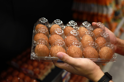 Cropped image of customer hands holding a box of egg in a grocery store