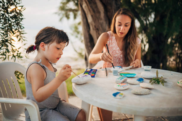 istock A mother  is doing activity with her daughter while sitting at a table on the beach 1435235257