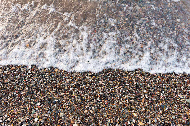 Pebble stones by the sea. Sea pebbles and wave on beach.