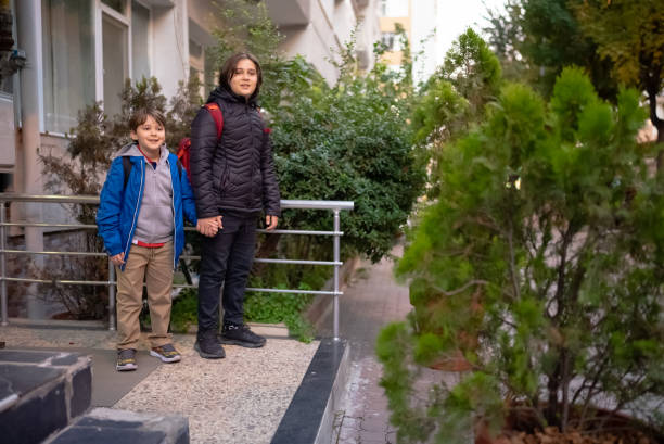 istock Boys waiting for school bus in street 1435237221