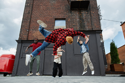 Action shot of all male breakdance team doing jumps in urban city setting