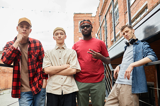 Diverse group of guys wearing street style and looking at camera in city, male hip-hop team