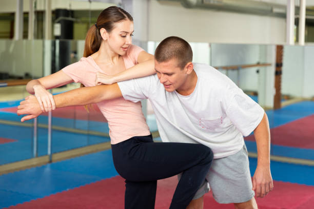 Woman performing knee strike during self-defence training Caucasian woman performing knee strike while sparring with man in gym during self-defence training. self defense stock pictures, royalty-free photos & images