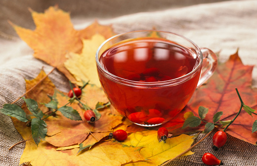 A cup of rose hip tea with fresh berries in a glass cup. Vintage background, selective focus.