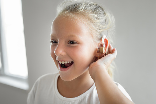 Smiling female child with a hearing aid behind the ear