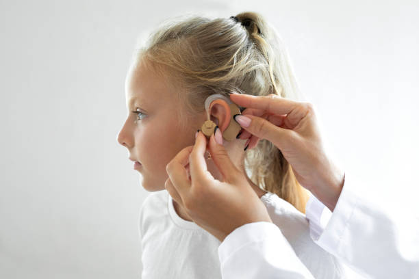 Doctor putting an hearing aid in a child's ear stock photo