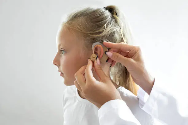 Photo of Doctor putting an hearing aid in a child's ear