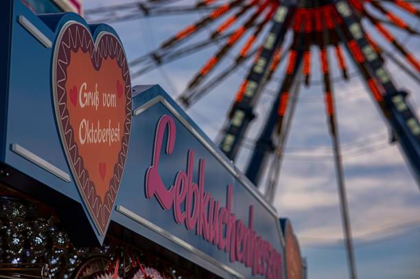 un'esposizione di un negozio di souvenir turistici all'oktoberfest di monaco con la ruota panoramica sullo sfondo - ferris wheel wheel oktoberfest carnival foto e immagini stock