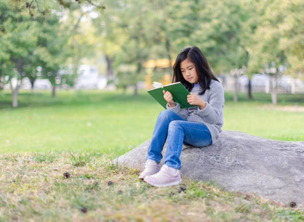 istock Reading Little Girl with Sitting on Stone 1435246213