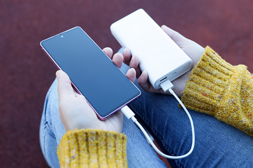 Smartphone in hand is charging from power bank