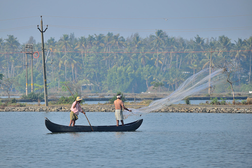 Kochi, India - February 21, 2018: Two Fisherman fishing on a boat in Cherai river.