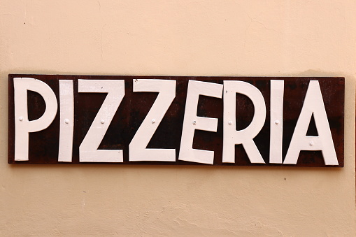Sign of a pizza restaurant in Florence in Tuscany hanging on the wall.