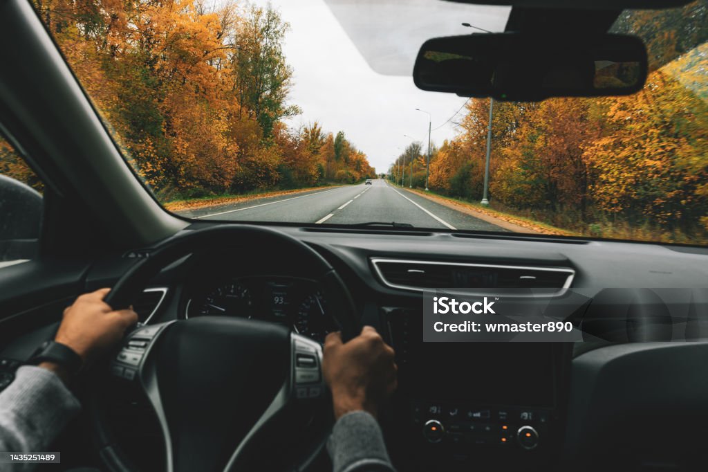 Man driving car on the country road in autumn. Man driving car on the country road in autumn. Rear view Driving Stock Photo