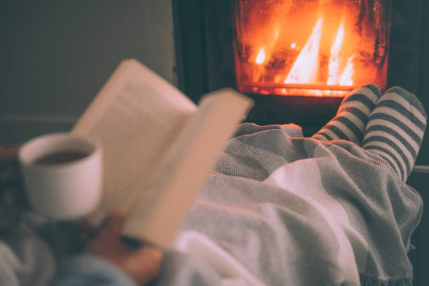 istock Man resting with hot drink cup and book near fireplace 1435251521