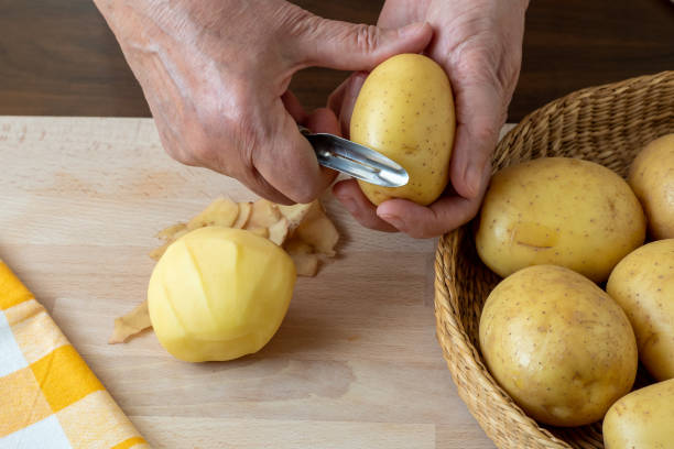 istock Hands peel potato, peelings on wooden cutting board. 1435255477