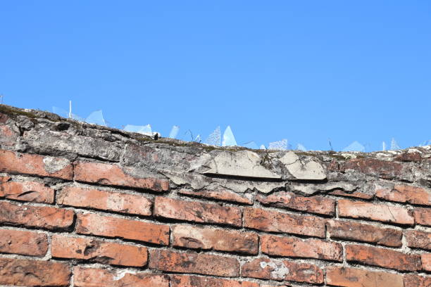 istock Rustic stone brick wall lined up as a texture and topped with pieces of glass. 1435256220