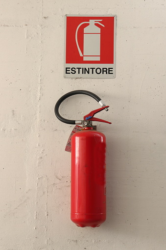 Red fire extinguisher hanging on the wall inside a garage