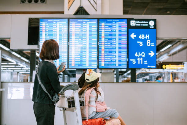 asiatische chinesische familie überprüft die boarding-zeit nach digitalem fahrplan - pre flight stock-fotos und bilder