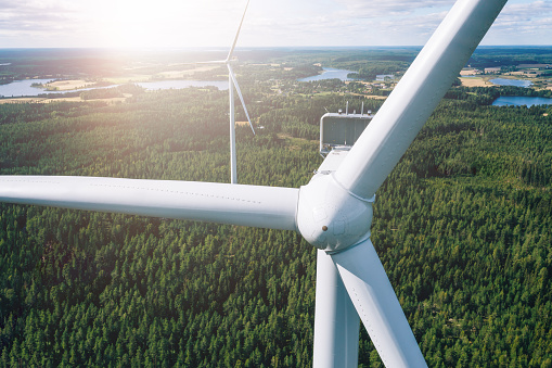 Aerial view of windmills in summer forest in Finland. Wind turbines for electric power with clean and Renewable Energy