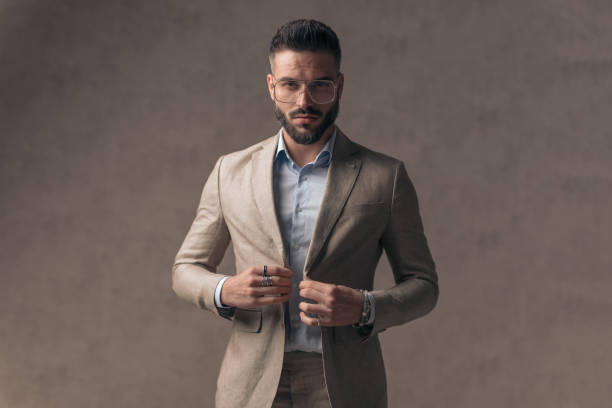 istock confident young man with glasses closing elegant suit and being cool 1435258244
