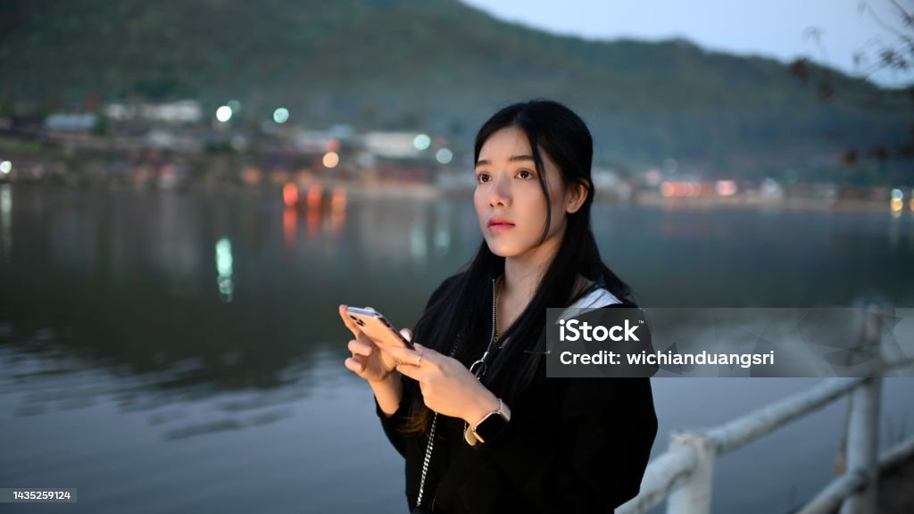 A young female tourist uses a mobile phone to see the nature. Mae Hong Son Province Stock Photo