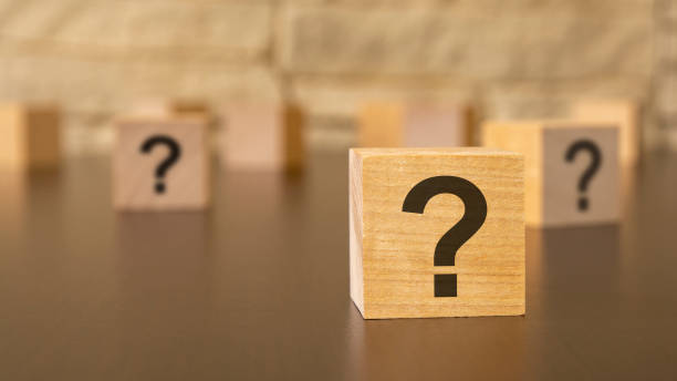 istock natural wooden cube with question marks, black background 1435259260