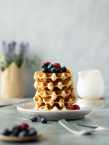 Stack of waffles with berries on a grey ceramic plate
