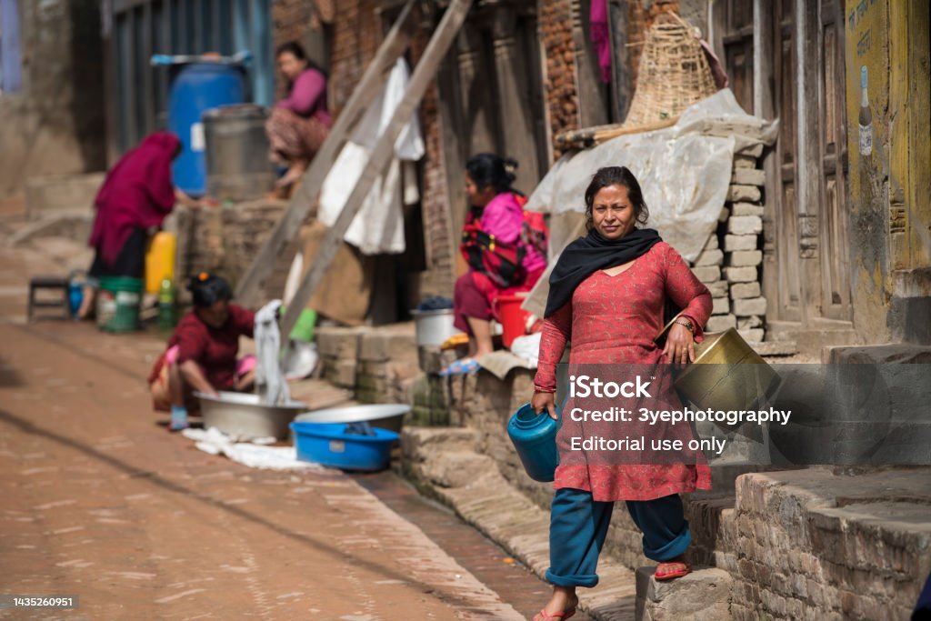 Women wash clothes and dishes on the streets in Kathmandu, Nepal. Kathmandu, Nepal- April 20,2022 : Women wash clothes and dishes on the streets of Patan Durbar Square. Adult Stock Photo