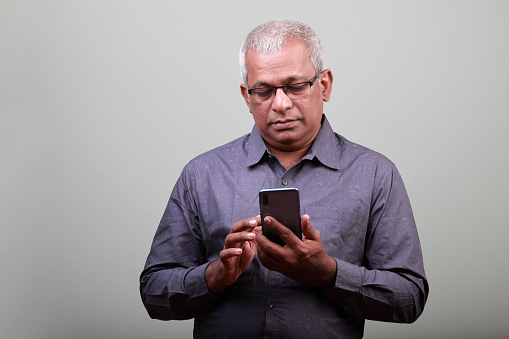 Portrait of a senior man of Indian ethnicity looking at mobile phone