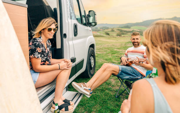 istock Friends having fun talking and playing ukulele in front of their camper van 1435264833