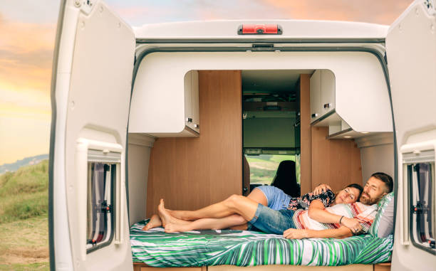 Couple sleeping embraced in the bed of their camper van with legs intertwined stock photo
