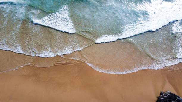 istock Aerial view of sea waves breaking sandy beach 1435268488