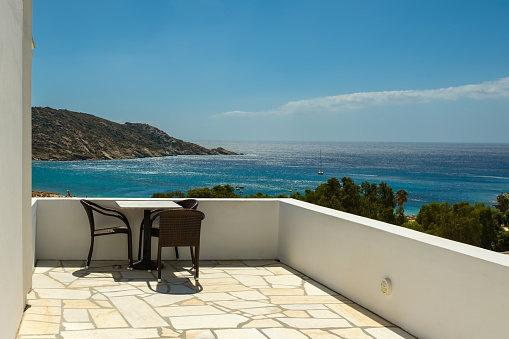 A balcony with chairs and a table overlooking the famous Mylopotas beach in Ios Greece