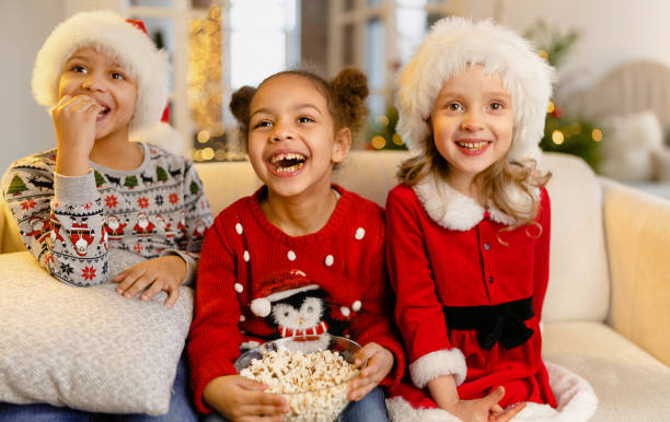 los niños ven películas en casa el día de navidad apuntando a la pantalla - carousel merry go round child african descent fotografías e imágenes de stock