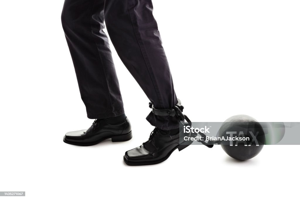 Tax ball and chain restraining businessman as he tries to walk concept for business financial burden, taxes and bankruptcy Tax ball and chain restraining a businessman as he tries to walk concept for business financial burden, taxes and bankruptcy Men Stock Photo