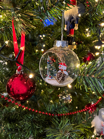 Festive Christmas and New Year celebration ornament concept: Close-up on beautiful xmas tree decoration lights, glass ball and toys hanging on artificial pine branches. Decorative holiday background, copy space.