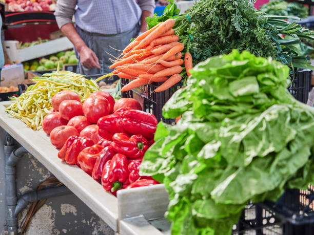 Selective focus on a bunch of carrots at a market stall. Vegetables from the garden Selective focus on a bunch of carrots at a market stall. Vegetables from the garden. People out of focus, not recognisable in the field. Person buying fresh fruit and vegetables merchants gate stock pictures, royalty-free photos & images