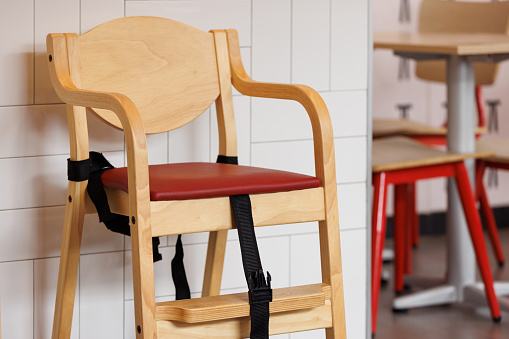 Wooden dinning chair with safety seat belts for baby. wooden high chair for kid eating in asian restaurant.