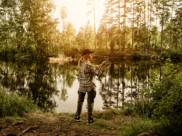 Man out in nature by a lake fishing with rod stock photo