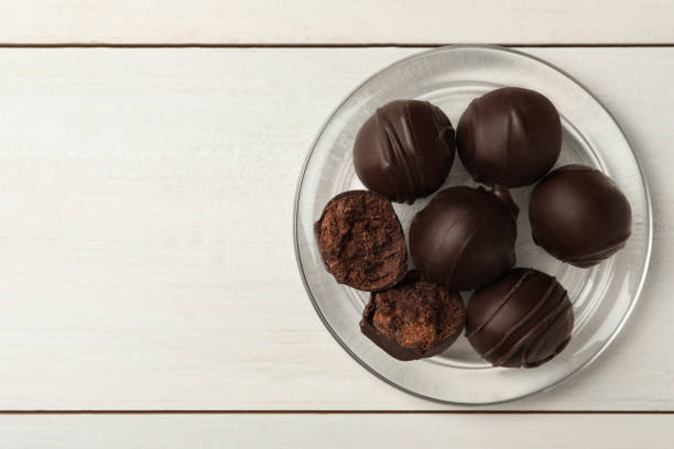istock Many delicious chocolate truffles on white wooden table, top view. Space for text 1435284822