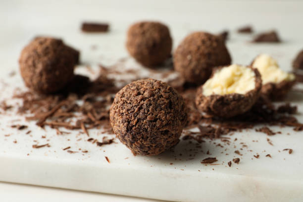 istock Many delicious chocolate truffles on white board, closeup 1435285668