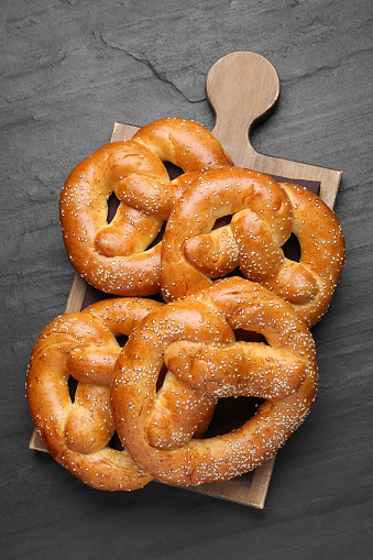 Delicious pretzels with sesame seeds on black table, top view