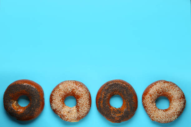 istock Many delicious fresh bagels on light blue background, flat lay. Space for text 1435286750