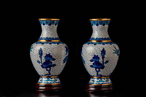 Antique brass paired cloisonné enamel Chinese vases on a black background.
