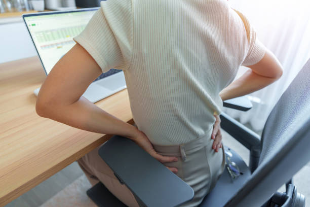 職場で長時間の仕事中に背中の体の痛みを抱える女性。梨状筋、腰痛、腰痛、腎臓、リウマチ、脊椎圧迫による。オフィス症候群と人間工学的コンセプト - low back ストックフォトと画像