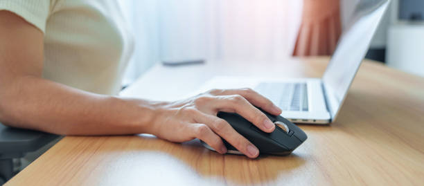 istock woman hand using ergonomic vertical mouse during working on Adjustable desk, prevention wrist pain. De Quervain s tenosynovitis, Intersection Symptom, Carpal Tunnel or Office syndrome concept 1435289293