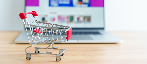 Shopping cart and laptop computer with marketplace website. business, technology, ecommerce, digital banking and online payment concept